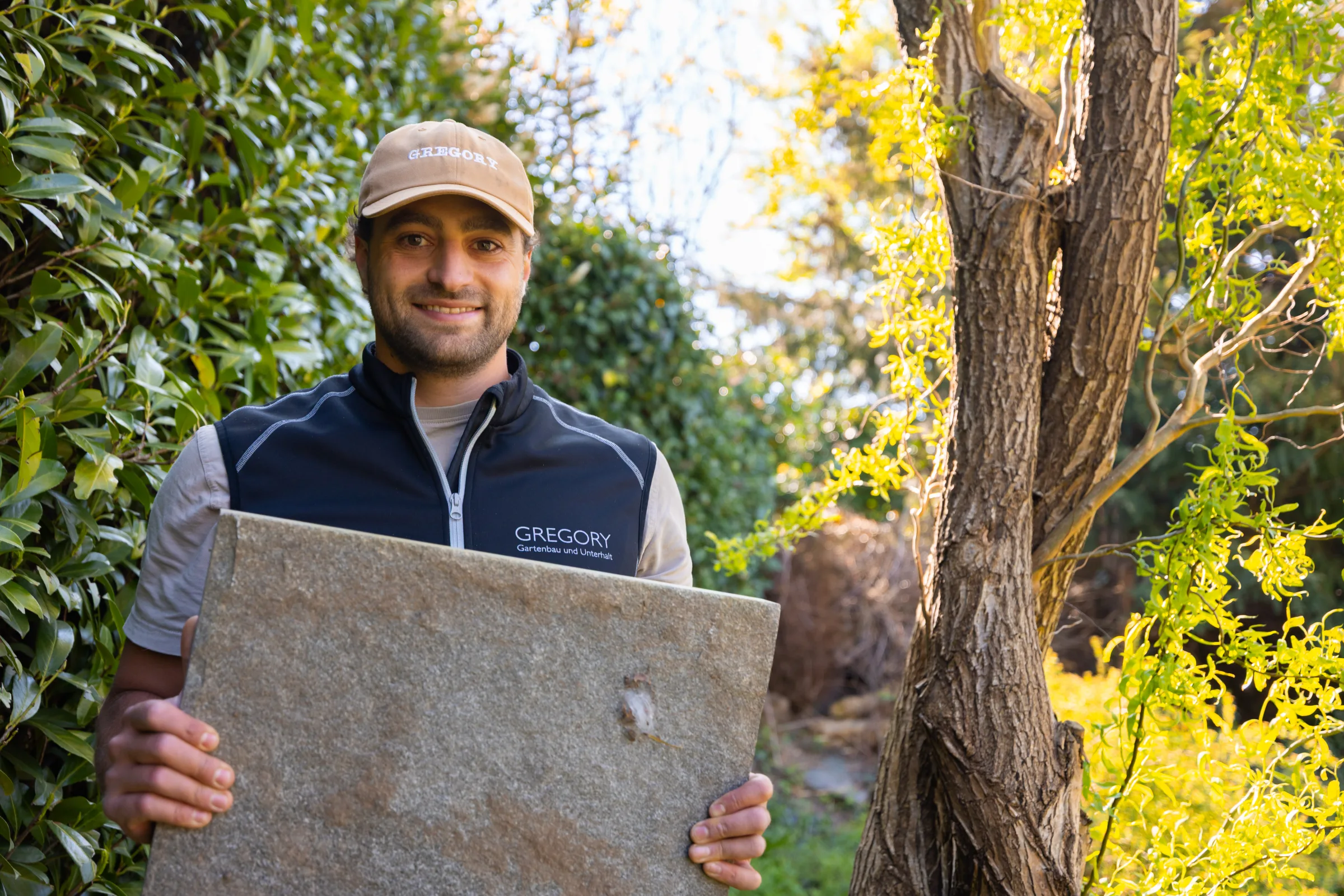 Gregory mit einer Sandstein-Platte in der Hand, Material-Auswahl auf der Baustelle