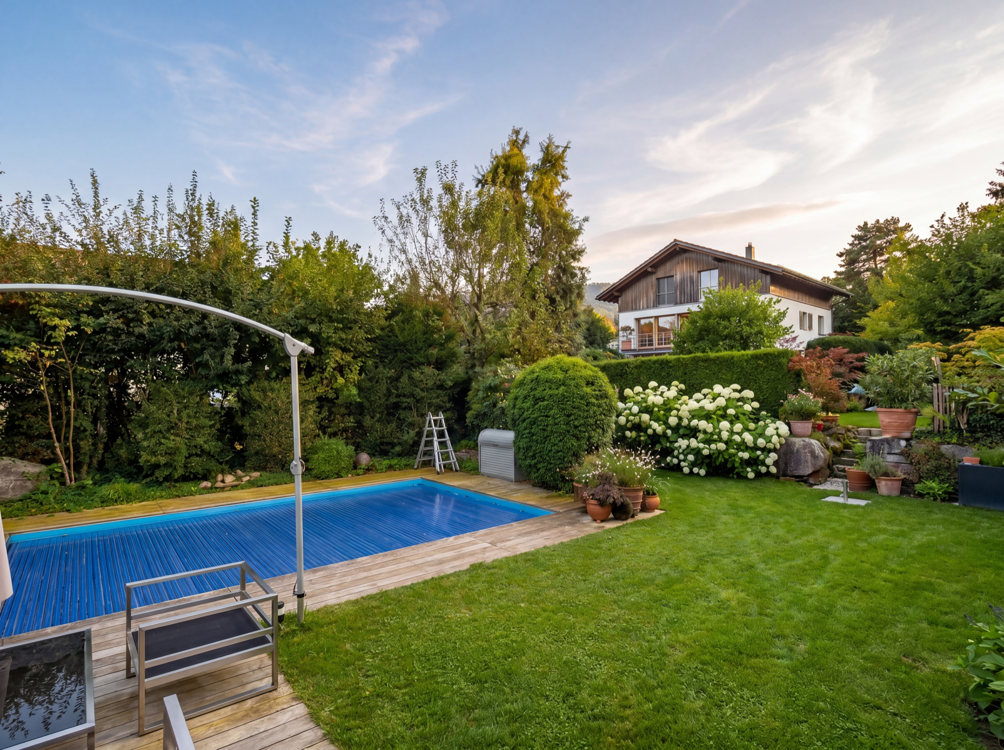 Pool-Garten mit Holzdeck, Hortensien und Sonnenschirm in Weitwinkel-Komposition, natürliches Sommerlicht