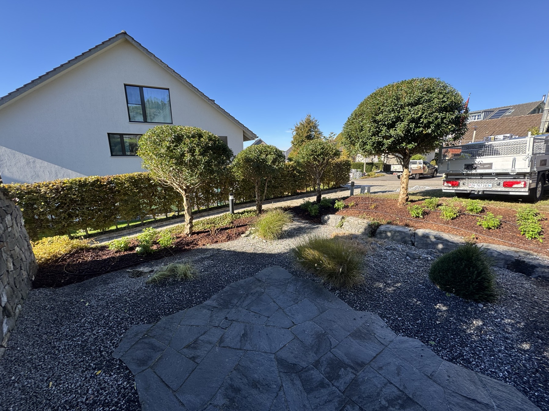 Gepflegter Garten mit Topiari-Sträuchern, Steinplatten und modernem EFH: echtes Gregory-Projekt in Adliswil